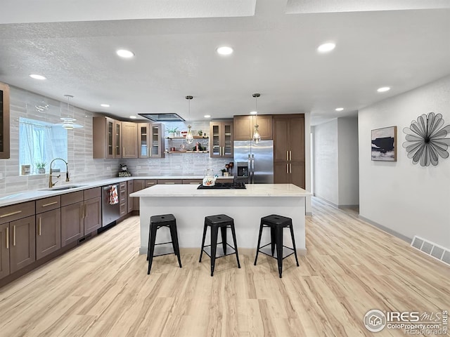 kitchen featuring a sink, visible vents, a kitchen breakfast bar, appliances with stainless steel finishes, and open shelves