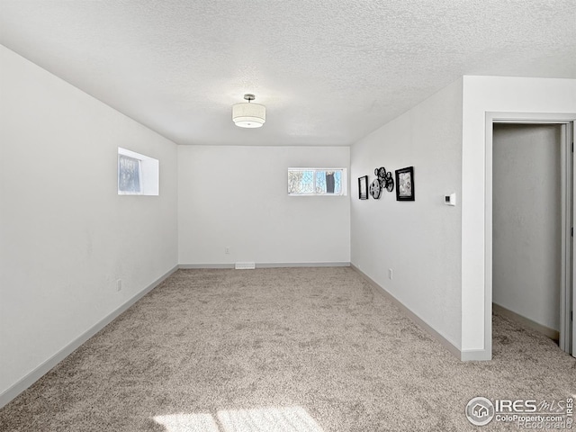 carpeted spare room with a textured ceiling and baseboards