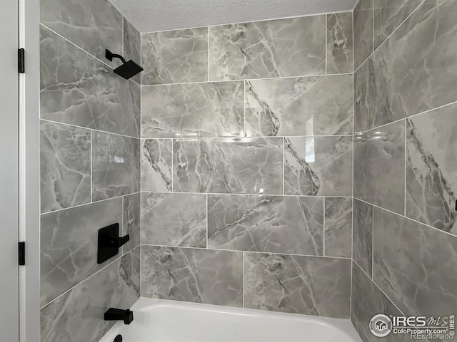 bathroom featuring washtub / shower combination and a textured ceiling