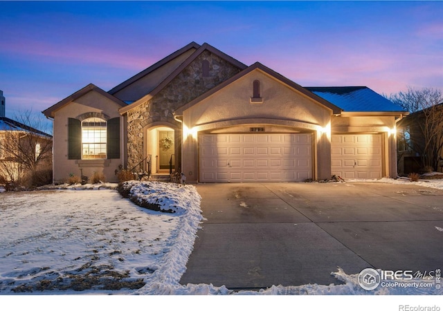 ranch-style house featuring a garage, stone siding, concrete driveway, and stucco siding