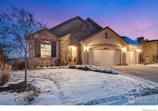 view of front of property featuring a garage, stone siding, driveway, and stucco siding