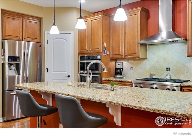 2185 Diamond Creek Dr, Colorado Springs, CO 80921 - kitchen with a breakfast bar, appliances with stainless steel finishes, light stone countertops, wall chimney exhaust hood, and pendant lighting