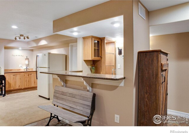 2185 Diamond Creek Dr, Colorado Springs, CO 80921 - kitchen with light carpet, visible vents, glass insert cabinets, freestanding refrigerator, and light stone countertops