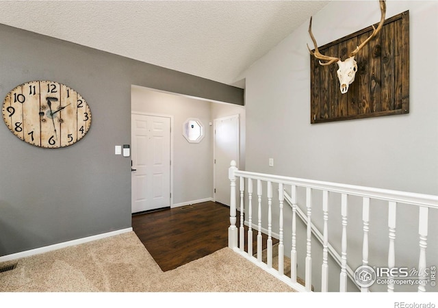 foyer featuring a textured ceiling, vaulted ceiling, dark carpet, and baseboards