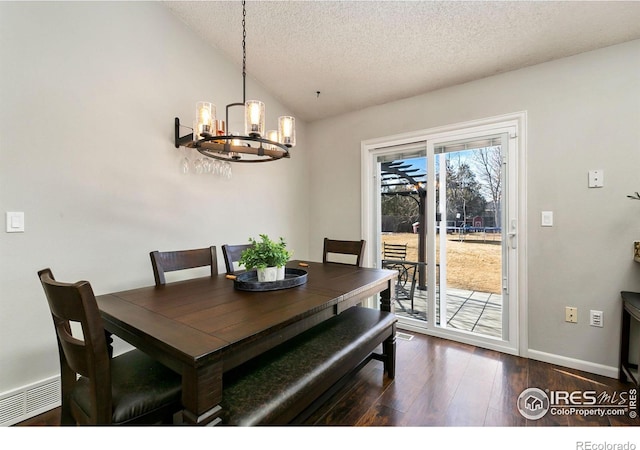 dining area featuring lofted ceiling, a textured ceiling, a notable chandelier, dark wood-style flooring, and baseboards