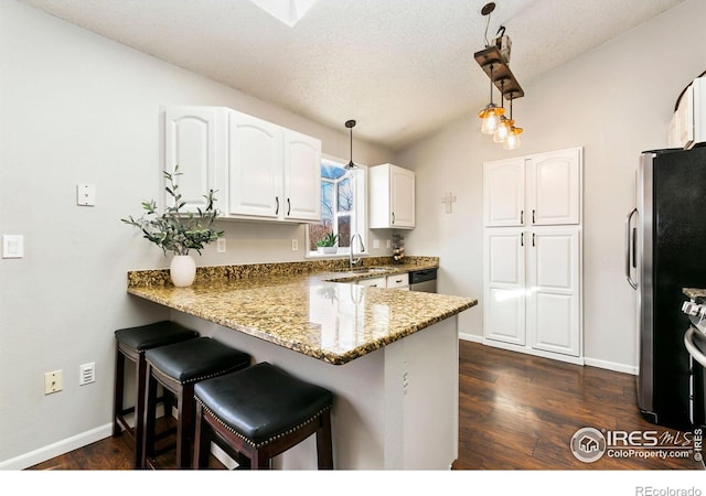 kitchen with dark stone counters, hanging light fixtures, a peninsula, stainless steel appliances, and white cabinetry