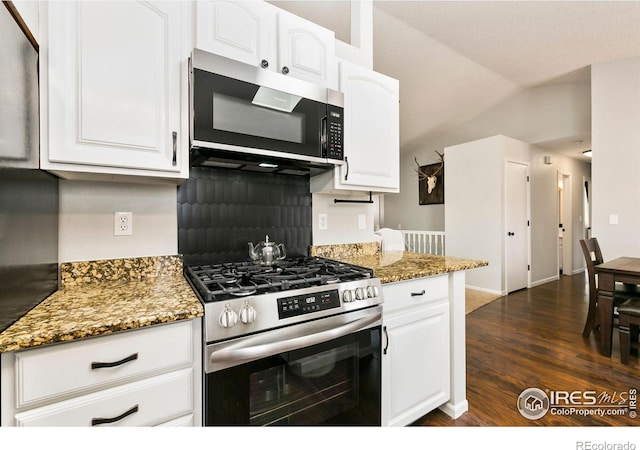 kitchen featuring stainless steel appliances, dark stone countertops, and white cabinetry