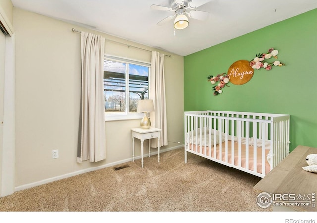 unfurnished bedroom with baseboards, visible vents, ceiling fan, carpet floors, and a nursery area