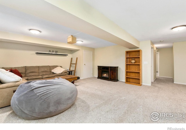 carpeted living room with a warm lit fireplace and baseboards