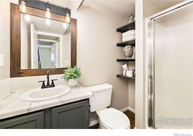 bathroom with toilet, a stall shower, and vanity