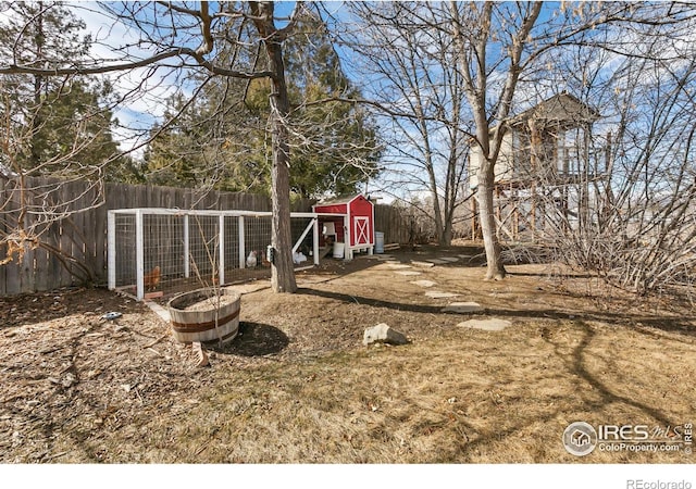 view of yard featuring fence, exterior structure, and an outbuilding