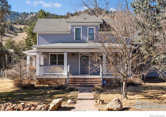 view of front facade with a porch, roof with shingles, and a mountain view