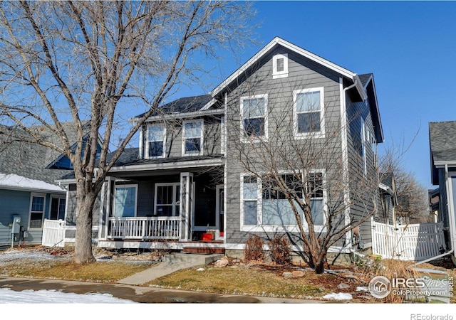 traditional home featuring covered porch and fence