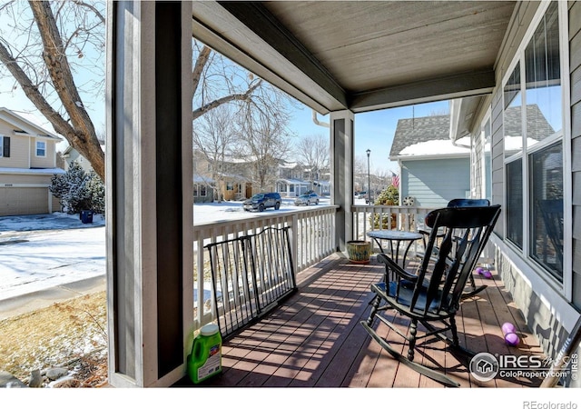 snow covered back of property featuring covered porch and a residential view