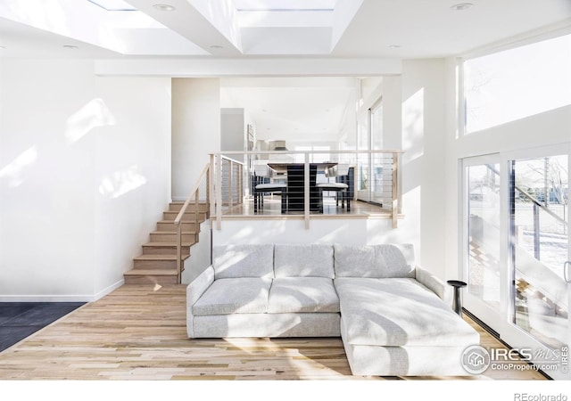 living room featuring stairs, baseboards, and wood finished floors