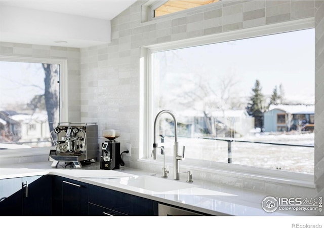 kitchen with a healthy amount of sunlight, a sink, tile walls, and dark cabinets