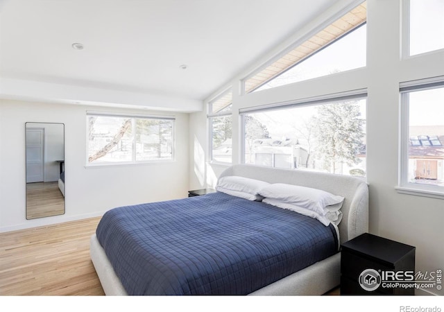 bedroom featuring lofted ceiling, light wood-type flooring, and baseboards