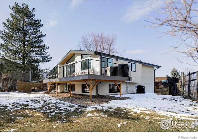 snow covered back of property with stairs, fence, a wooden deck, central AC, and stucco siding