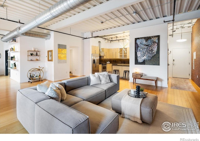 living room featuring light wood-type flooring and a towering ceiling