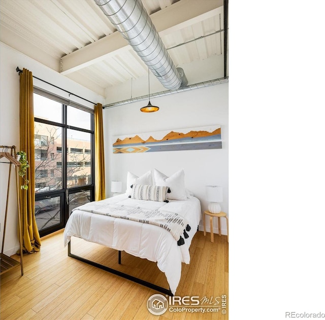 bedroom with beamed ceiling and wood finished floors