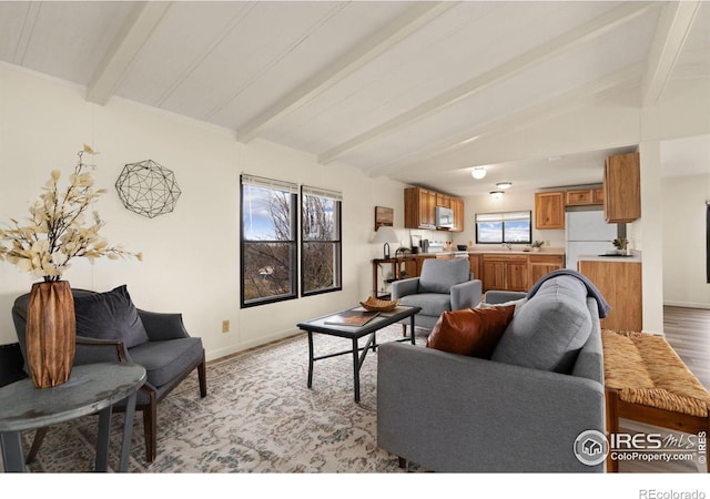 living room with lofted ceiling with beams, baseboards, and light wood-style floors