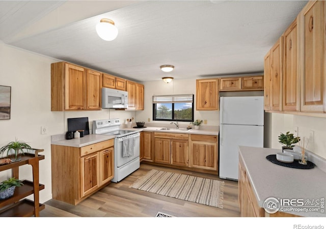 kitchen with white appliances, light countertops, a sink, and light wood finished floors