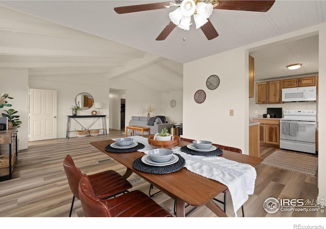 dining room with lofted ceiling with beams and light wood finished floors