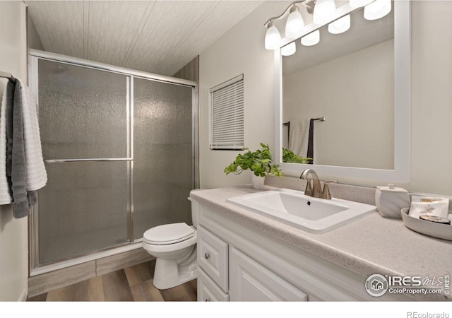 bathroom featuring vanity, wood finished floors, toilet, and a shower stall