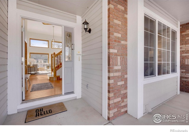 doorway to property featuring a porch and brick siding