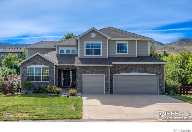 view of front of house featuring a shingled roof, a front yard, a mountain view, and an attached garage