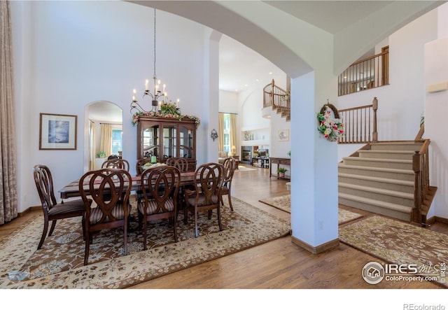 dining area featuring arched walkways, a high ceiling, wood finished floors, stairs, and a wealth of natural light