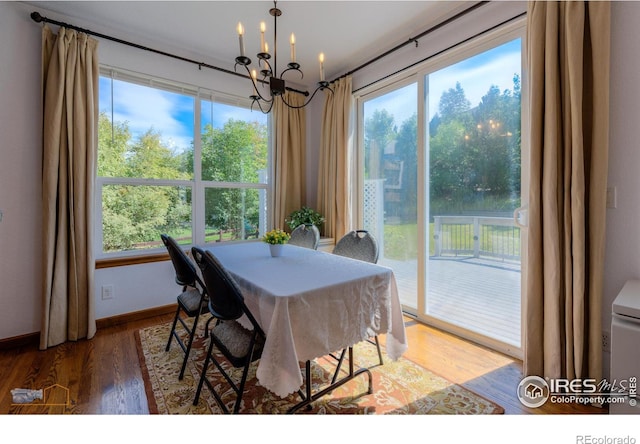 dining space with a chandelier, baseboards, wood finished floors, and a healthy amount of sunlight