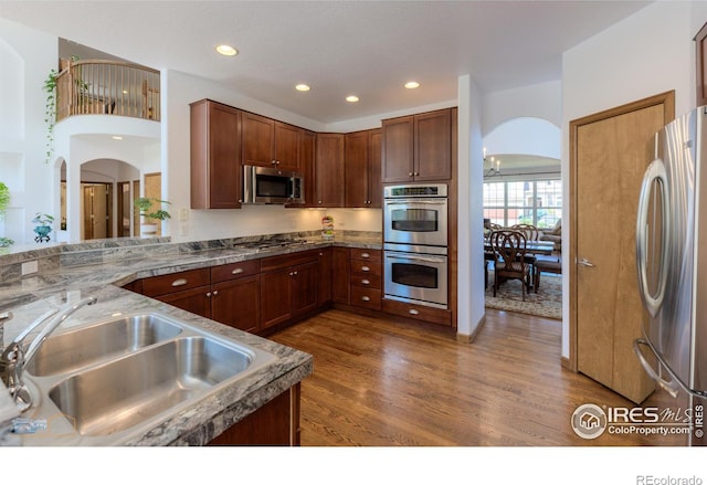 kitchen with arched walkways, dark wood-style flooring, recessed lighting, appliances with stainless steel finishes, and a sink