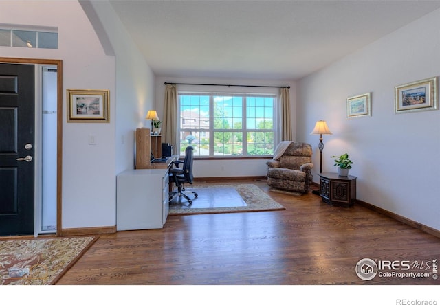 office area featuring baseboards, arched walkways, and dark wood-style flooring