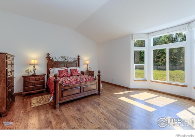 bedroom with dark wood-style floors, lofted ceiling, and baseboards