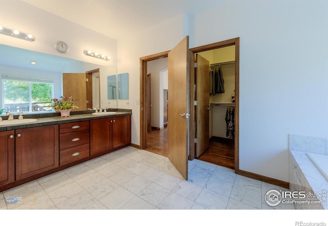 bathroom with double vanity, marble finish floor, a spacious closet, and a sink