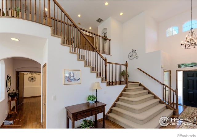 staircase featuring arched walkways, recessed lighting, wood finished floors, visible vents, and an inviting chandelier