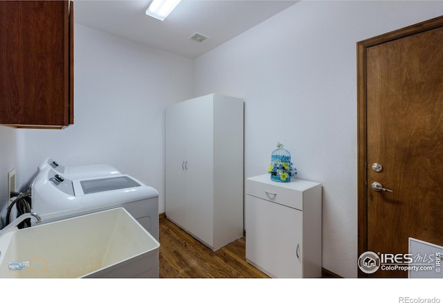 laundry room featuring dark wood-style flooring, a sink, visible vents, cabinet space, and washing machine and clothes dryer