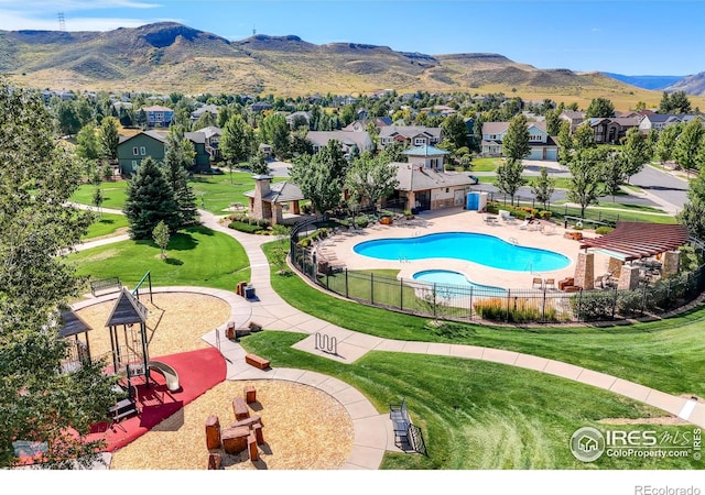 community pool with a yard, a residential view, fence, and a mountain view