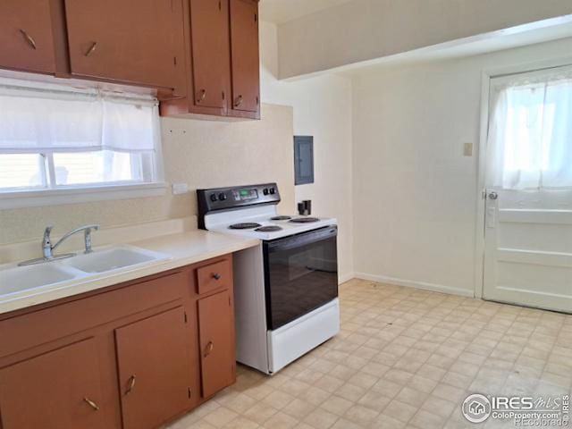 kitchen featuring brown cabinets, light floors, white range with electric cooktop, light countertops, and a sink