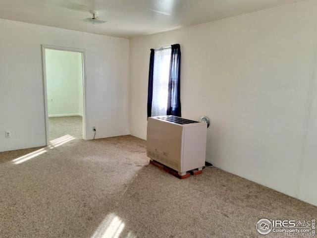 carpeted spare room featuring heating unit