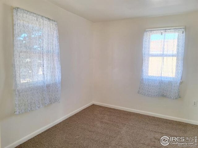 carpeted empty room featuring baseboards