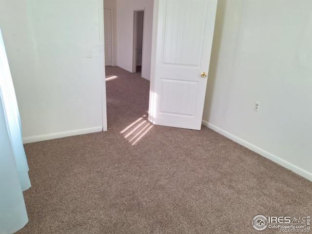 unfurnished room with carpet flooring and baseboards