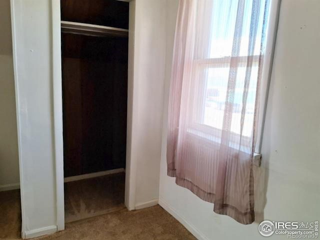 carpeted bedroom featuring baseboards and a closet