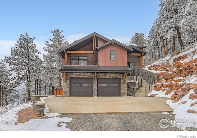 view of front of house featuring a garage, stairs, driveway, stone siding, and board and batten siding