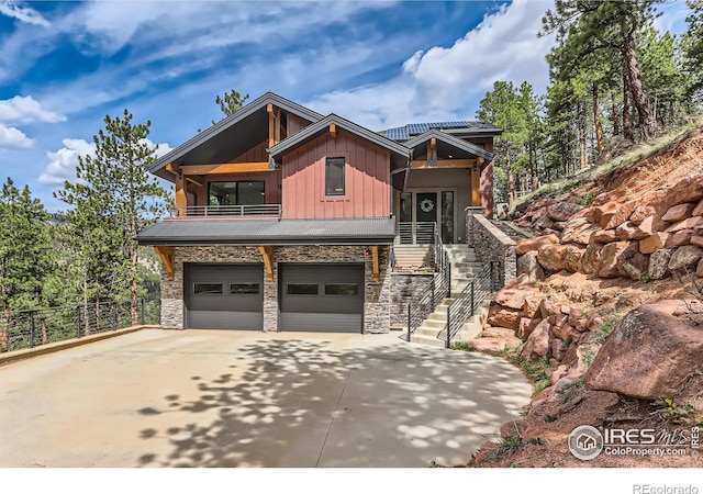 view of front of house featuring board and batten siding, driveway, a balcony, and stone siding