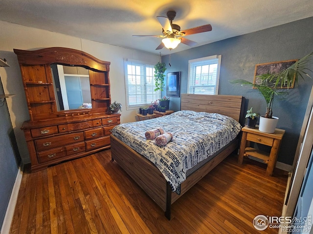 bedroom featuring ceiling fan, a textured wall, dark wood-type flooring, and baseboards