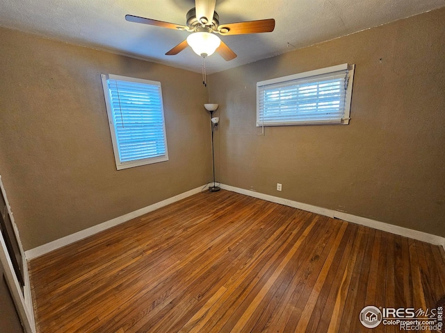 unfurnished room featuring a ceiling fan, hardwood / wood-style flooring, and baseboards