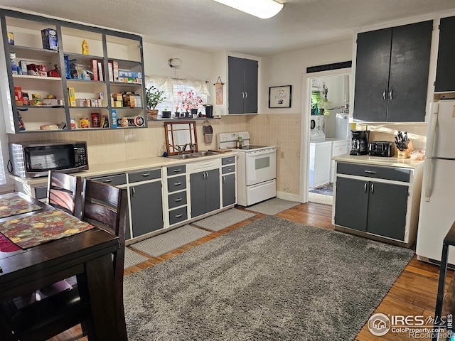 kitchen with dark cabinets, white appliances, washer and dryer, light countertops, and dark wood-style floors