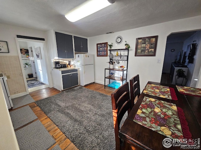 dining area with dark wood-style floors, visible vents, and a textured ceiling